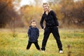 Young mother and son in autumn forest park, yellow foliage. Casual wear. Kid wearing blue jacket. Incomplete family Royalty Free Stock Photo