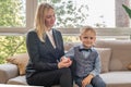 A young mother with a son of five years sits on the couch and holds the childs hand