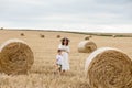 Young mother and son walking near stacks of straw - stacked bales of hay left after harvesting, farm field with Royalty Free Stock Photo