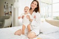 A happy young mother is hugging her newborn son while sitting on a large white bed Royalty Free Stock Photo