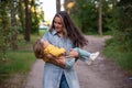 young mother is spinning with a baby in her arms. happy mom dancing with toddler on the background of nature and forest