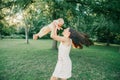 Young mother spinning toddler baby boy outdoors. Parent playing with child son in park. Authentic lifestyle funny moment. Happy