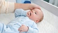 Young mother stroking her little baby son lying on dressing table in bedroom Royalty Free Stock Photo