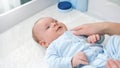 Young mother stroking her little baby son lying on dressing table. Concept of hygiene, baby care and healthcare Royalty Free Stock Photo