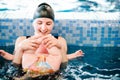 Young mother, swimming instructor and happy little girl in the pool. Teaches infant child to swim. Enjoy the first day of swimming Royalty Free Stock Photo