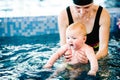 Young mother, swimming instructor and happy little girl in the pool. Teaches infant child to swim. Enjoy the first day of swimming Royalty Free Stock Photo