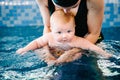 Young mother, swimming instructor and happy little girl in the pool. Teaches infant child to swim. Enjoy the first day of swimming Royalty Free Stock Photo