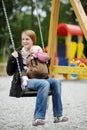 Young mother on a swing with baby