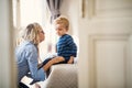 A young mother talking to her toddler son inside in a bedroom. Royalty Free Stock Photo