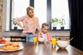 young mother talking with upset little daughter sitting at table