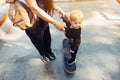 Young mother teaches her little boy to ride a skateboard