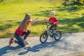 Young mother teaching her son how to ride a bicycle in the park Royalty Free Stock Photo