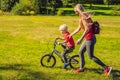 Young mother teaching her son how to ride a bicycle in the park Royalty Free Stock Photo