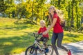 Young mother teaching her son how to ride a bicycle in the park Royalty Free Stock Photo