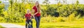 Young mother teaching her son how to ride a bicycle in the park BANNER, LONG FORMAT Royalty Free Stock Photo