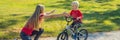 Young mother teaching her son how to ride a bicycle in the park BANNER, LONG FORMAT Royalty Free Stock Photo