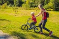 Young mother teaching her son how to ride a bicycle in the park Royalty Free Stock Photo