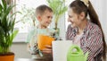 Young mother teaching her son transplanting flowers in pots at home. Concept of gardening, hobby, home planting. Royalty Free Stock Photo