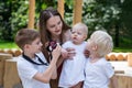 Young mother and three children in the Park. Eldest son is taking pictures siblings. Big happy family