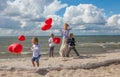 Young mother and three children with red balloons
