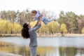 Young mother throws up baby in the sky, on sunny day. Royalty Free Stock Photo