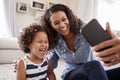 Young mother and toddler daughter taking selfie at home