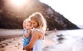 Young mother with a toddler girl on beach on summer holiday at sunset. Royalty Free Stock Photo