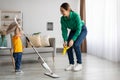 Young mother and toddler son cleaning at home together, mom teaching kid chore help home work