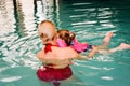 Young mother trying to learn to swim on her little daughter in the indoor pool . Vintage filter