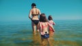 Mother and two adorable daughters are standing in the sea