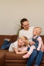 Young mother and two children sitting on couch. Happy family concept. Vertical frame Royalty Free Stock Photo