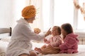 Young mother two daughters in curlers bathrobes. happy smiling family skin care concept. Mom teaches little kids child Royalty Free Stock Photo