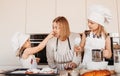 A young mother and two daughters have fun in the kitchen and play with flour Royalty Free Stock Photo