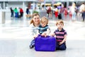 Young mother with two little kid boys at airport. Cute preschool children, siblings, twins and woman, family traveling