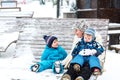 Young mother with two little toddler boys sitting on bench in winter park. Woman playing and hugging with cute baby sons Royalty Free Stock Photo
