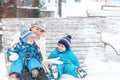 Young mother with two little toddler boys sitting on bench in winter park. Woman playing and hugging with cute baby sons Royalty Free Stock Photo