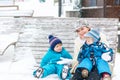 Young mother with two little toddler boys sitting on bench in winter park. Woman playing and hugging with cute baby sons Royalty Free Stock Photo