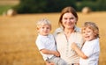 Young mother and two little twins boys having fun on yellow hay Royalty Free Stock Photo