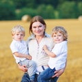 Young mother and two little twins boys having fun on yellow hay Royalty Free Stock Photo