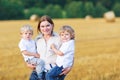 Young mother and two little twins boys having fun on yellow hay Royalty Free Stock Photo