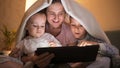 Young mother with two sons covering under blanket and watching video on tablet computer at night. Family having time together, Royalty Free Stock Photo