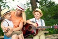 Young mother and two sons are resting in the woods,singing songs with a guitar.