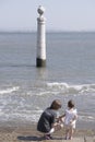 a young mother and a two year old girl contemplate at a seagull perched on a column on a pier above the Tagus estuary in Lisbon, Royalty Free Stock Photo