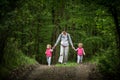 Young mother walk with identical twins in woods, young pretty girls with blond curly hair, freedom, joy, movement, outdoor Royalty Free Stock Photo