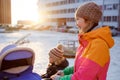 Young mother walking with baby child stroller in winter at sunset. Royalty Free Stock Photo