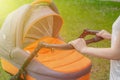 A young mother is walking with a baby stroller in a summer park on a sunny day Royalty Free Stock Photo