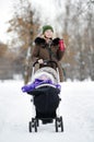 Young mother walking with baby in stroller in winter Royalty Free Stock Photo