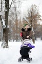 Young mother walking with baby in stroller in winter park Royalty Free Stock Photo