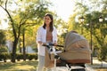 Young mother walking with her baby in stroller at park on sunny day Royalty Free Stock Photo