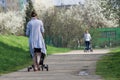 Young mother walking in park with baby in trolley